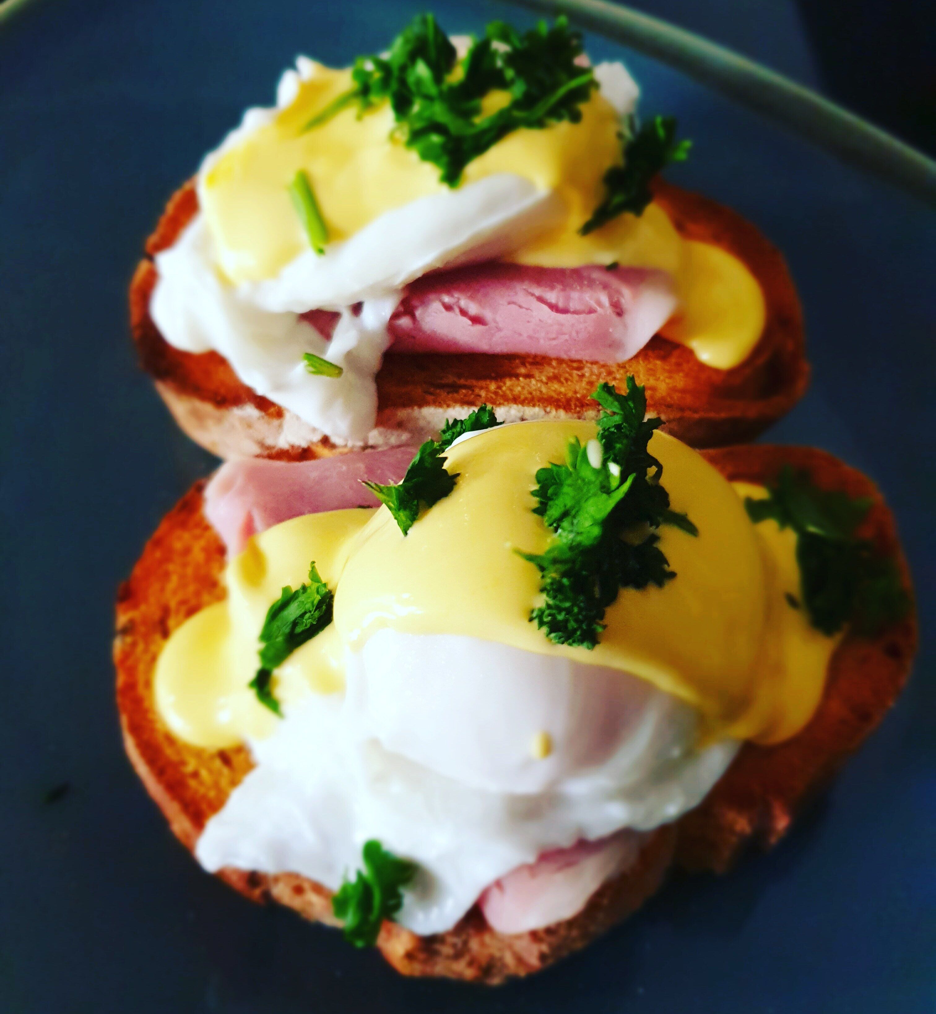 A sandwich with poached eggs and hollandaise sauce on toast, garnished with parsley.
