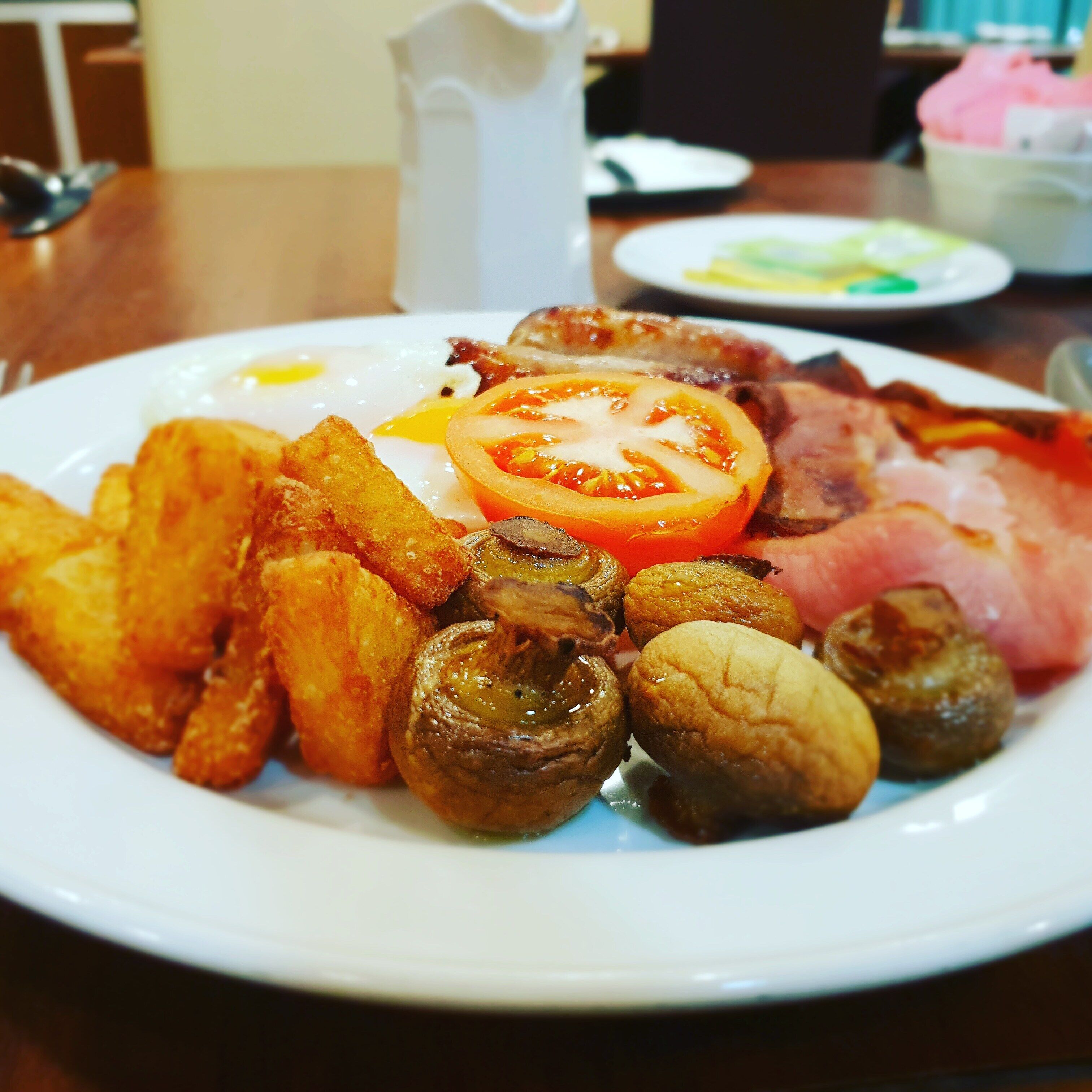 Un plato de desayuno con huevos, tocino, champiñones y papas asadas.