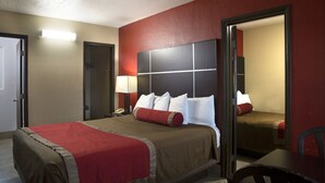 Ein Hotelzimmer mit einem großen Bett, einem Nachttisch, einem Sessel und einem Spiegel.