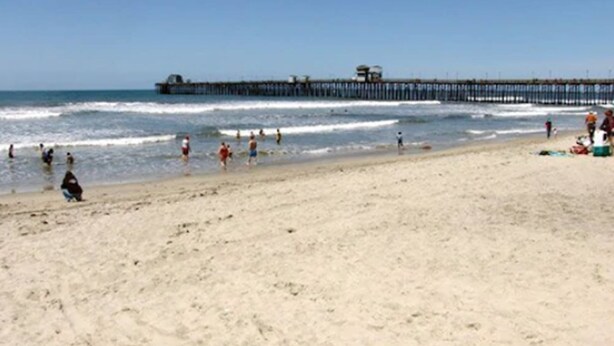 Ein Strand mit einem Steg, der sich ins Wasser erstreckt.