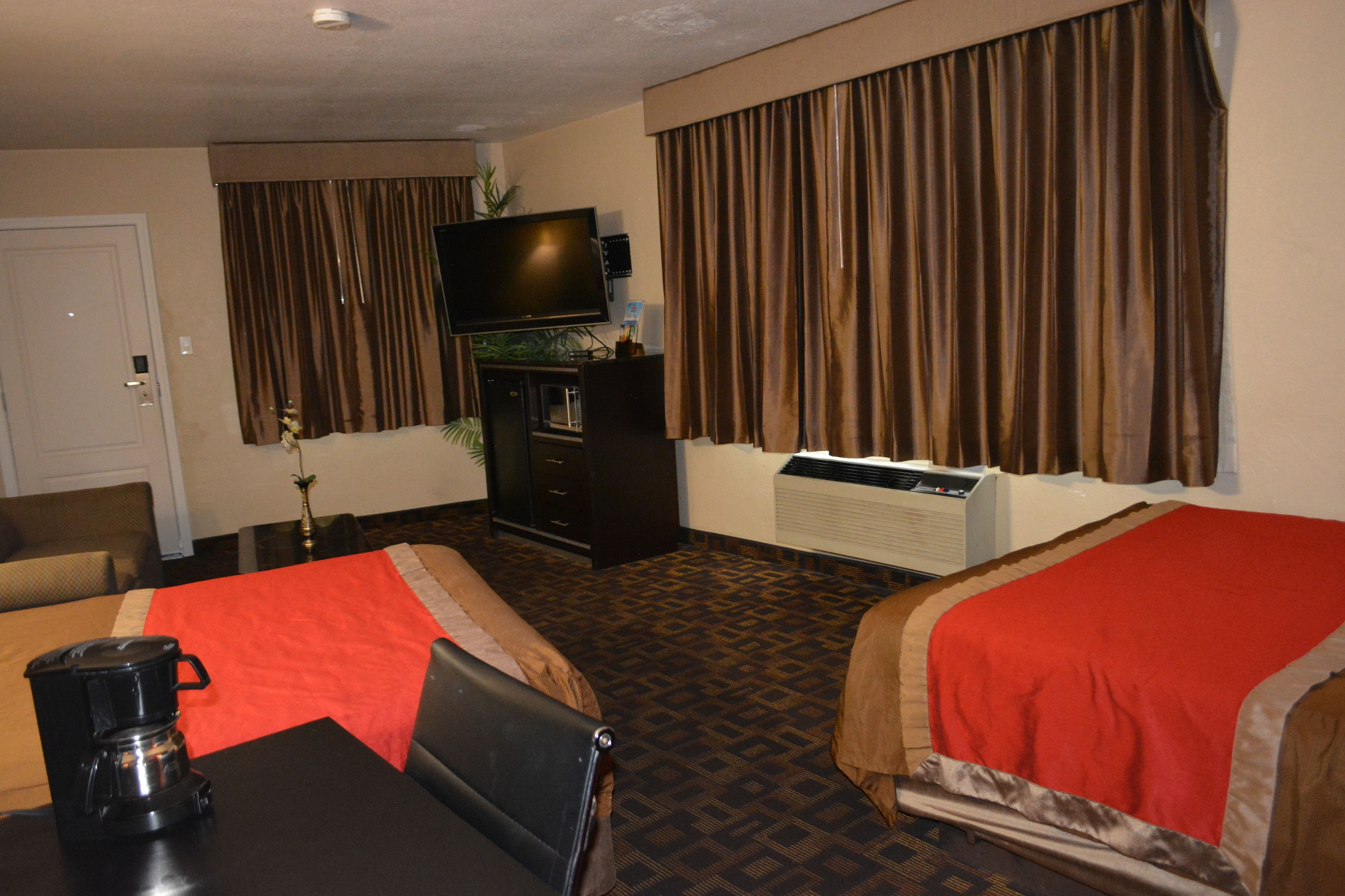 Habitación de hotel con dos camas, televisión, cafetera y escritorio.
