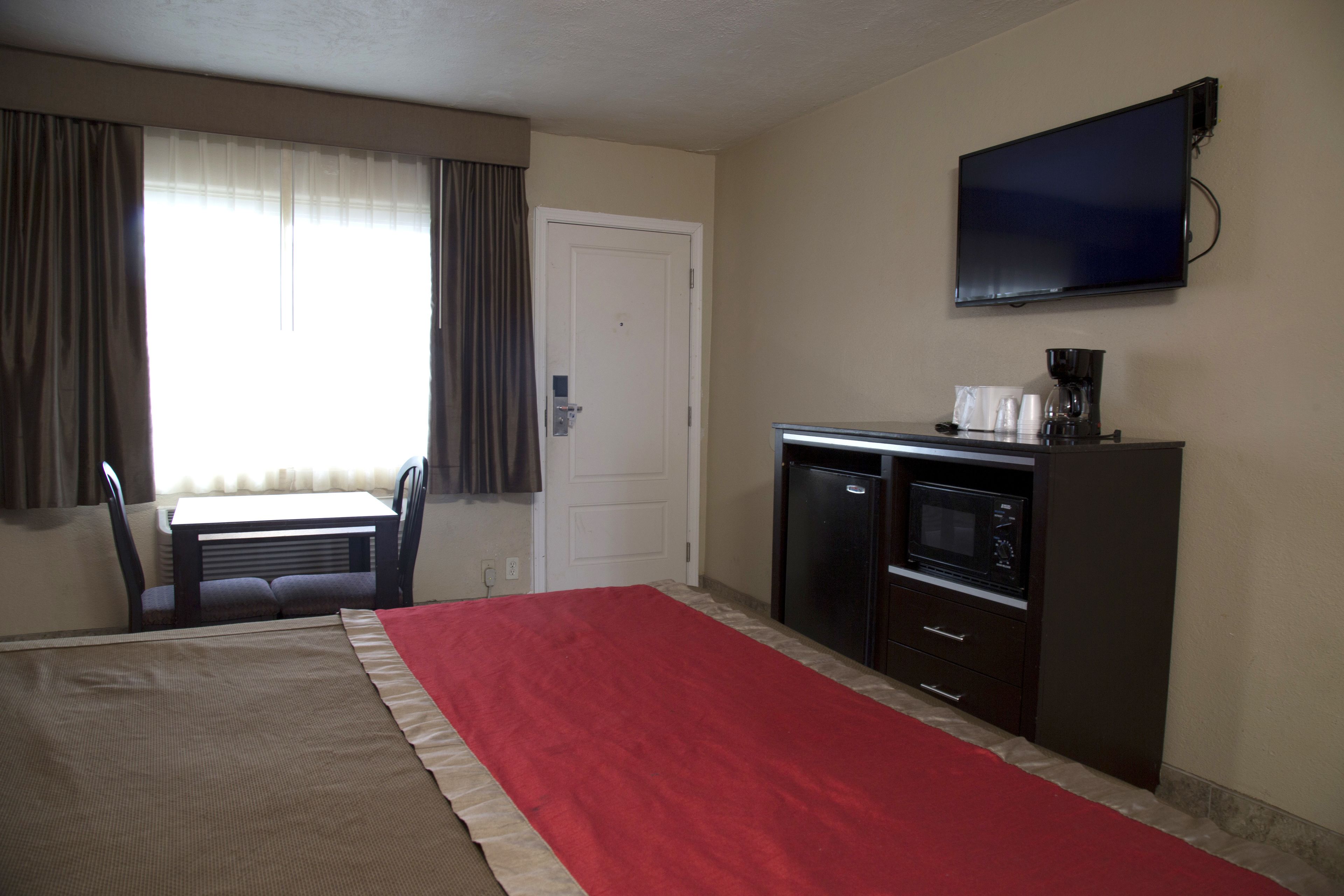 A hotel room with a bed, a desk, a television, and a kitchenette.