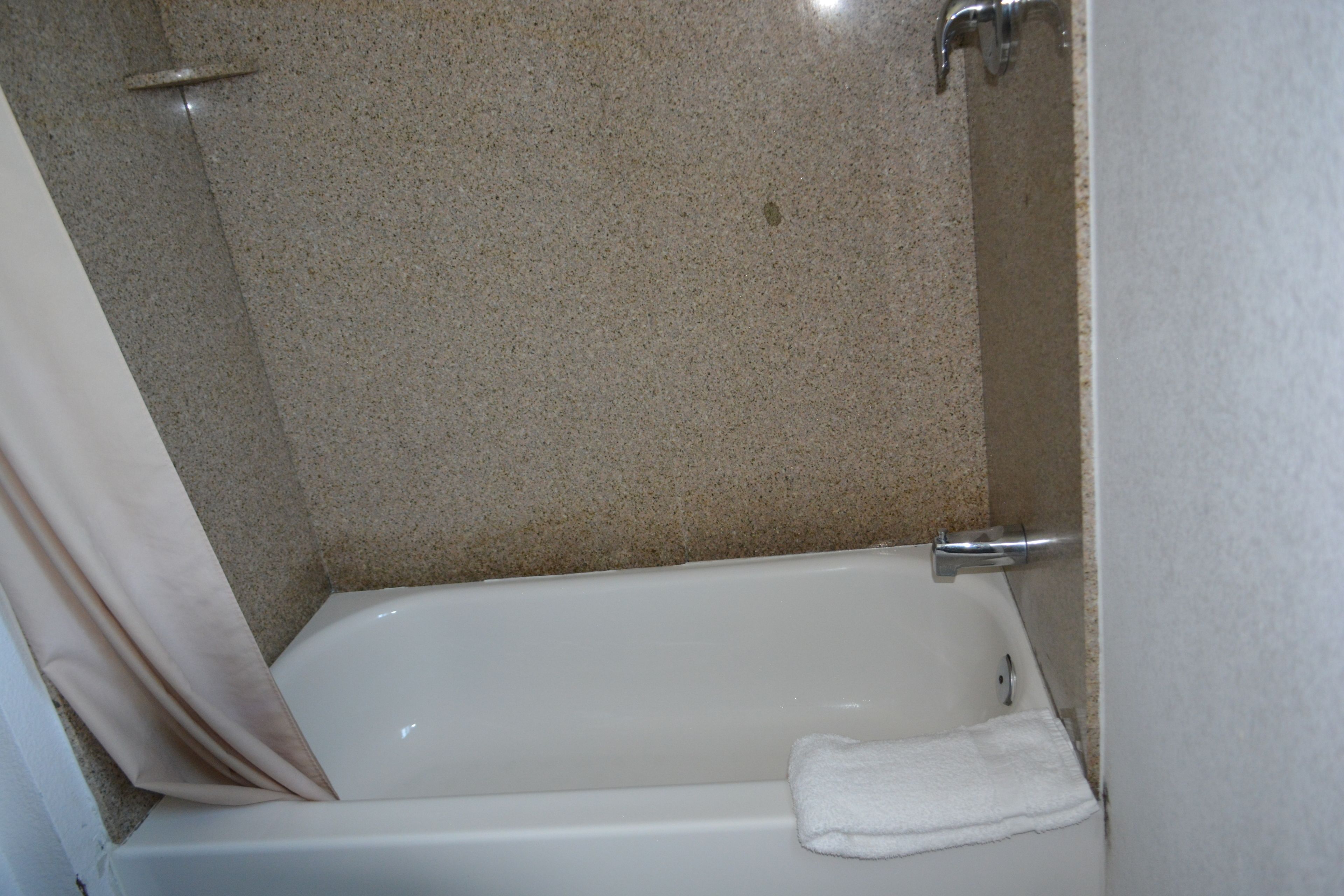 Une salle de bain avec une baignoire, une douche et une serviette accrochée au mur.