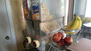 Ein Frühstücksbuffet mit Müsli, Äpfeln, Orangen und Bananen.