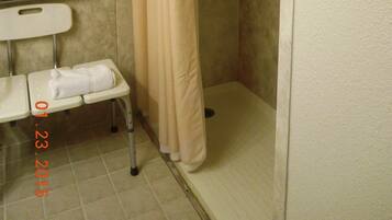 A shower stall with a beige curtain, a grab bar, and a bench with a towel.