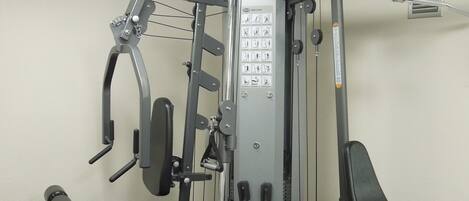 A gym with a multi-station workout machine, a bench, and a wall-mounted pull-up bar.