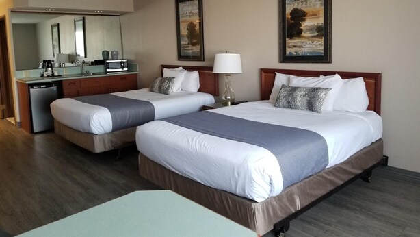 A hotel room with two beds, a desk, a microwave, and a sink. There are two paintings on the wall. - Shilo Inn Suites - Salem (Salem)