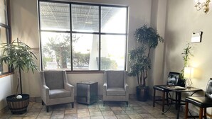 A room with two armchairs, a small table, and a dining table with chairs. There are potted plants and a chandelier. - Shilo Inn Suites - Salem (Salem)