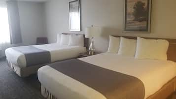 A hotel room with two beds, a nightstand, a lamp, and a painting on the wall.