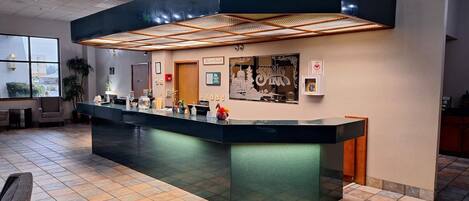 A reception area with a modern counter, a large window, and a wall-mounted sign.