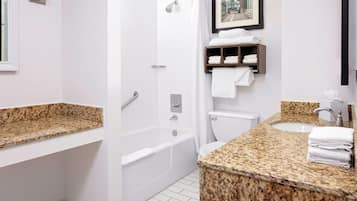 A modern bathroom with a granite countertop, a bathtub, a toilet, and a shower.