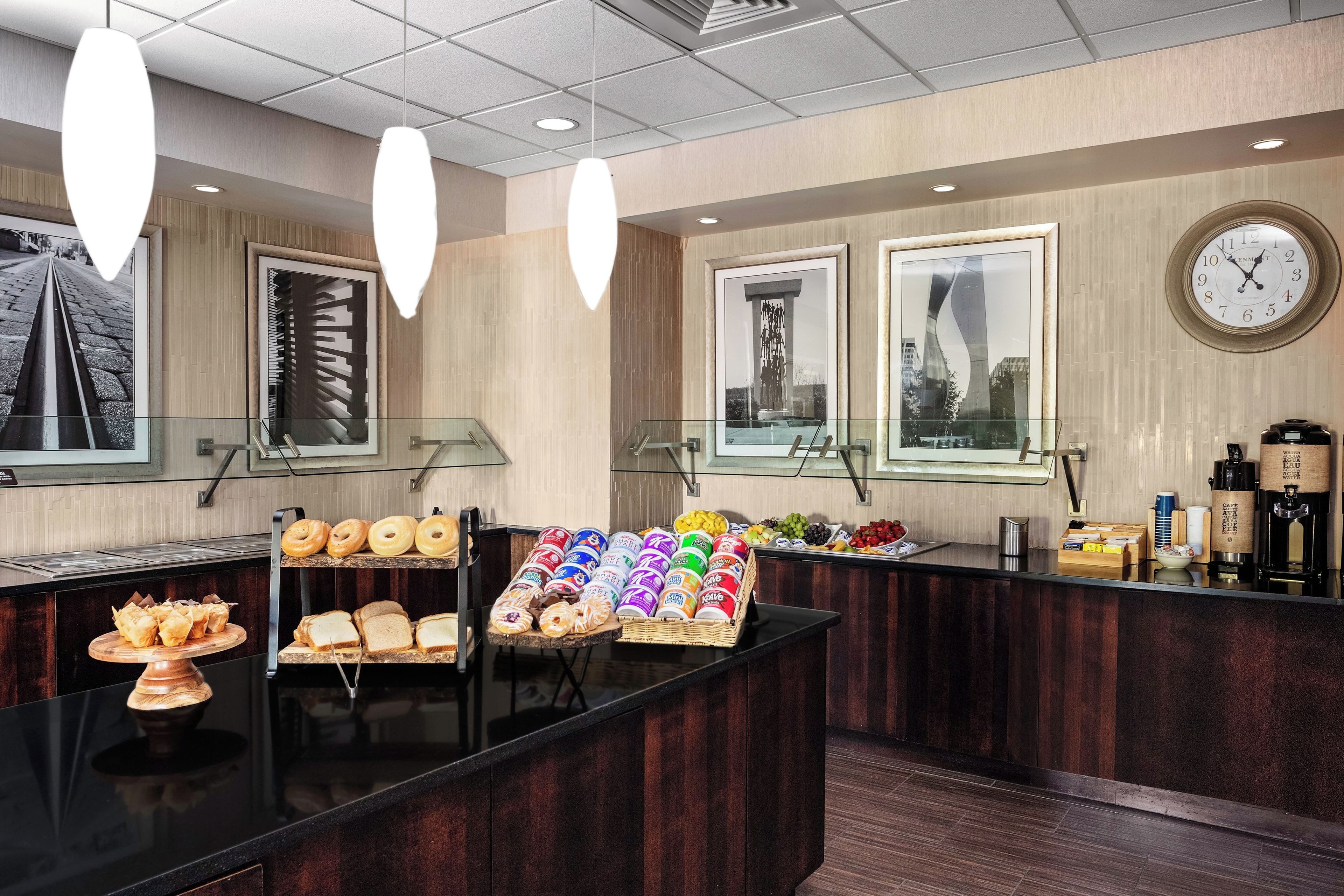 A hotel reception area with a counter displaying pastries, a clock, and framed artwork on the wall.