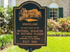 A sign with a building illustration and text stating Graceland is on the National Register of Historic Places, built in 1939.