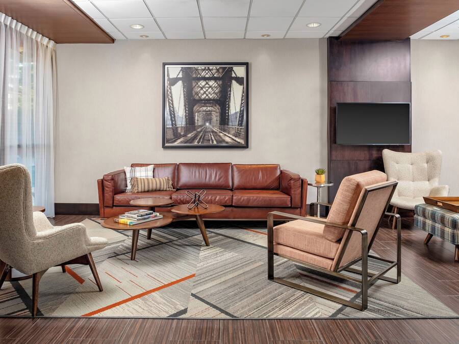 Ein modernes Wohnzimmer mit einer Ledersofa, einem Couchtisch und einem großen Gemälde einer Brücke.