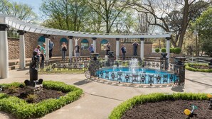 A courtyard with a central fountain, surrounded by a brick wall with arched windows, and a covered seating area. - Four Points by Sheraton Memphis East (Memphis)
