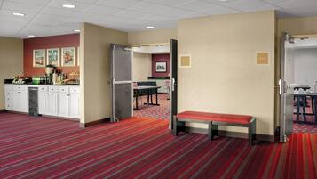 A hotel room with a kitchenette, a dining area, a bench, and a door labeled 'DELTA II'.