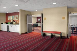 A hotel room with a kitchenette, a dining area, a bench, and a door labeled 'DELTA II'.