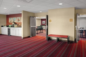 A hotel room with a kitchenette, a dining area, a bench, and a door labeled 'DELTA II'.