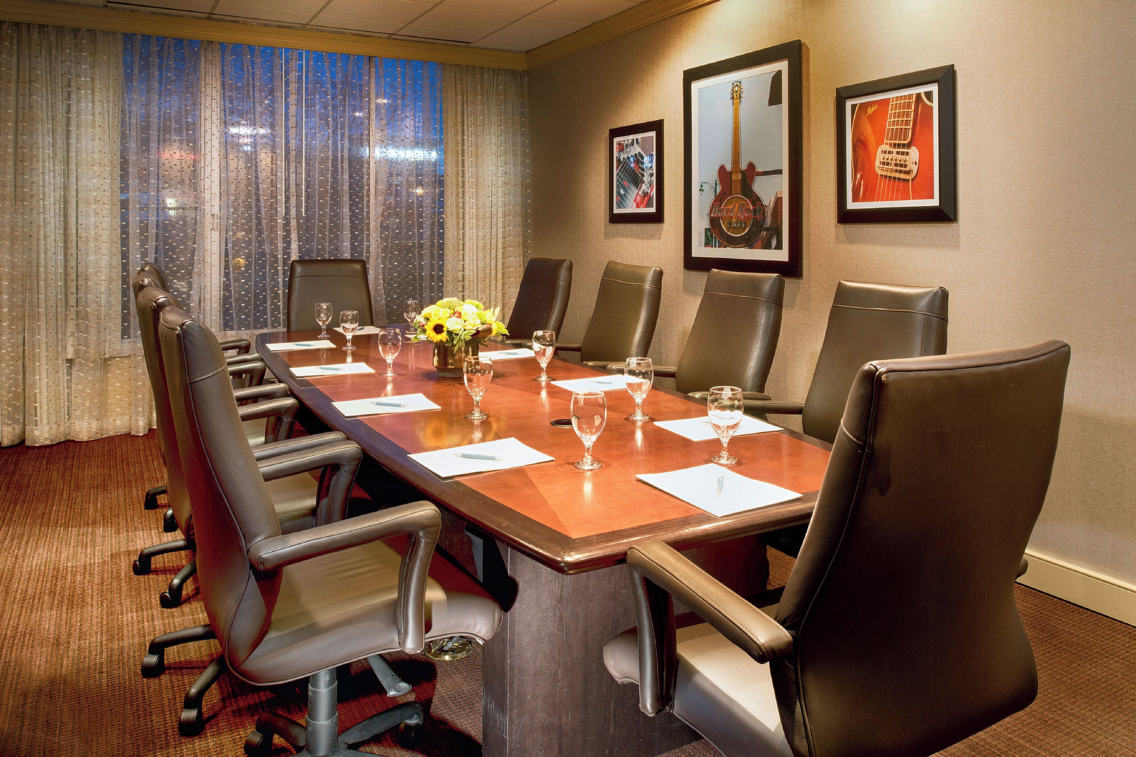 A conference room with a long table, multiple chairs, and framed pictures on the wall.