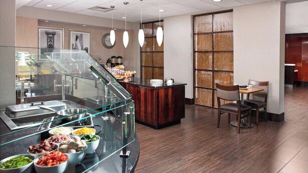 A buffet area with various food options, a seating area with chairs, and a counter with a coffee machine. - Four Points by Sheraton Memphis East (Memphis)