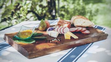 A wooden board with various cheeses, a pear, and bread on a table with a blue and white striped cloth.