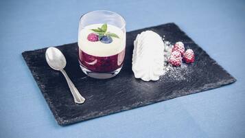 Dessert med glas, hindbær og flødeskum på en skiferplade.