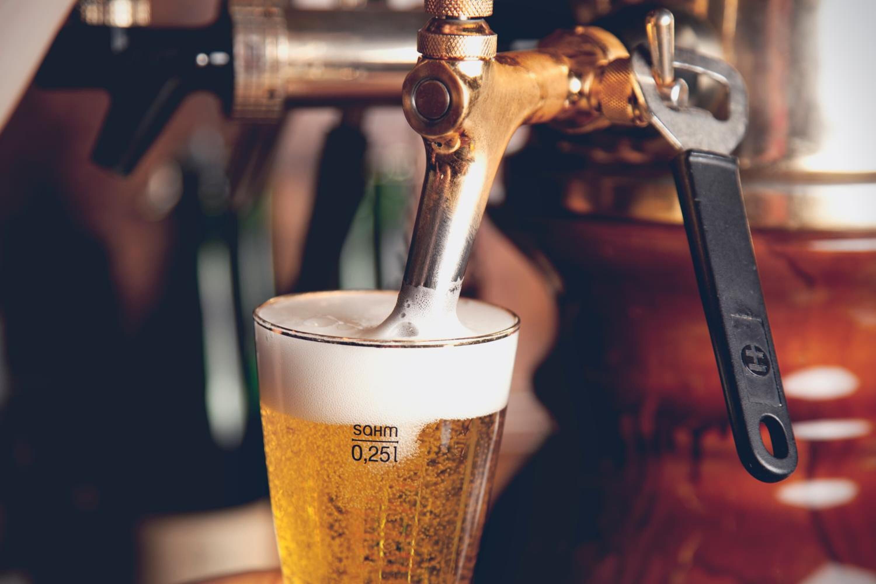 Um close-up de uma torneira de cerveja servindo cerveja em um copo.