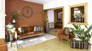 A living room with a brown sofa, two armchairs, a coffee table, a clock, and a potted plant. - Hotel de Chailly (Montreux)