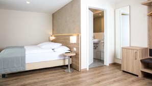 A modern hotel room with a bed, bedside table, mirror, and a wooden cabinet. - Hotel de Chailly (Montreux)