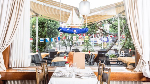 A restaurant with tables set for dining, a hanging lantern, and a view of the street outside. - Hotel de Chailly (Montreux)