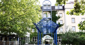 Une structure métallique bleue se trouve dans une cour, avec un bâtiment en arrière-plan.