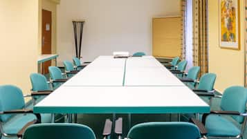 A conference room with a long table, teal chairs, a projector, and a whiteboard.