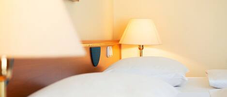 Una habitación de hotel con una cama, una lámpara de noche y un teléfono.