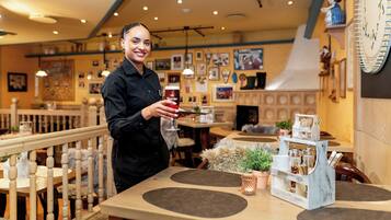 Une personne tenant un verre de bière dans un restaurant dont le mobilier est en bois et qui est décoré d’une horloge murale.