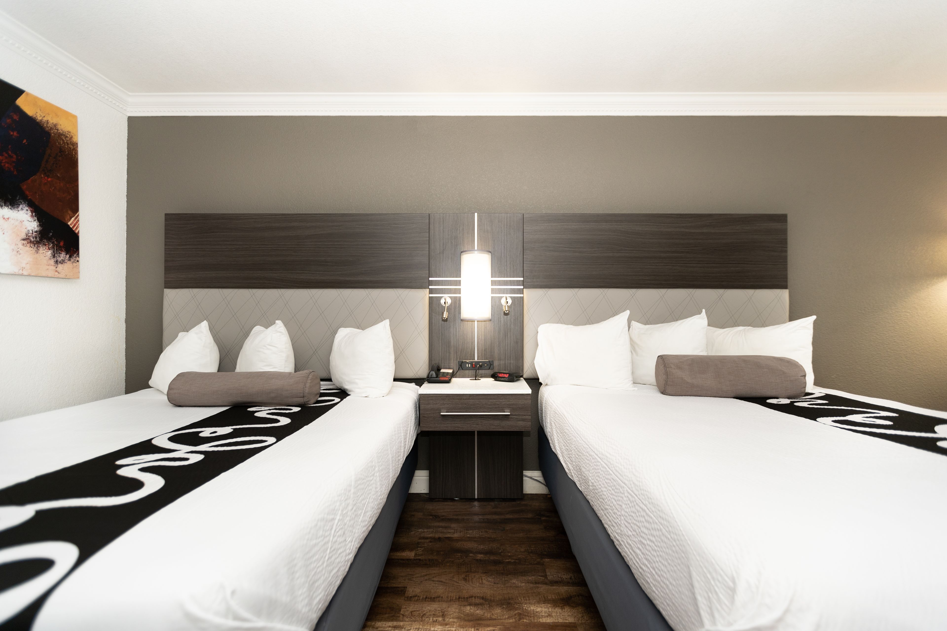Een hotelkamer met twee bedden, een nachtkastje, een spiegel en een wandlamp.