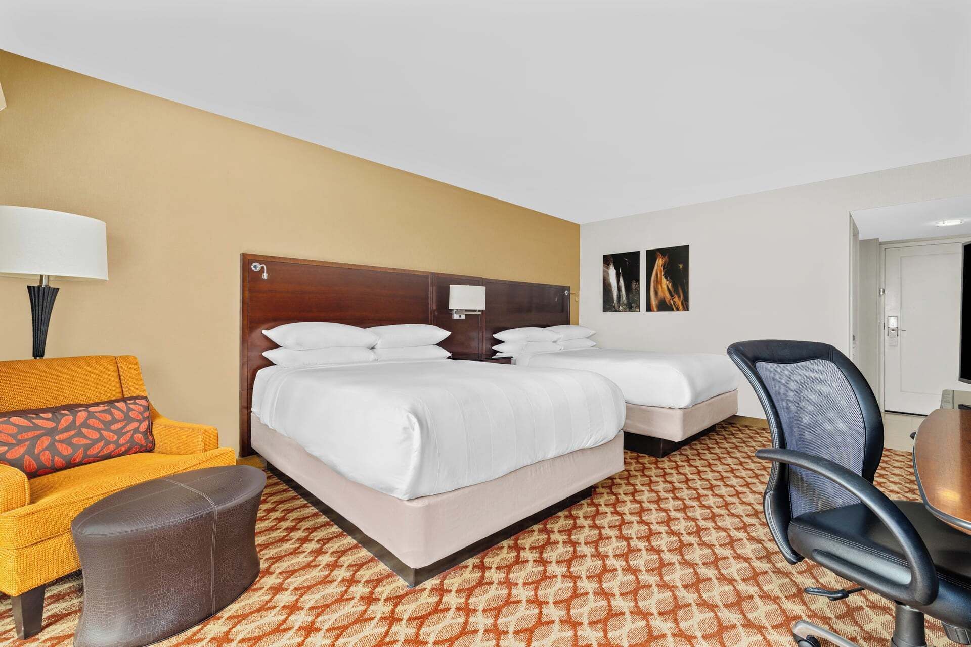 A hotel room with two beds, a sofa, a chair, and a lamp.