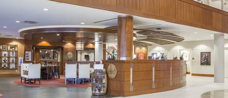 A spacious lobby with a reception desk, seating area, and a high ceiling with wooden paneling.