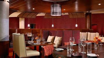 Un restaurante con cabinas y mesas, techo de madera y paredes rojas con textura.