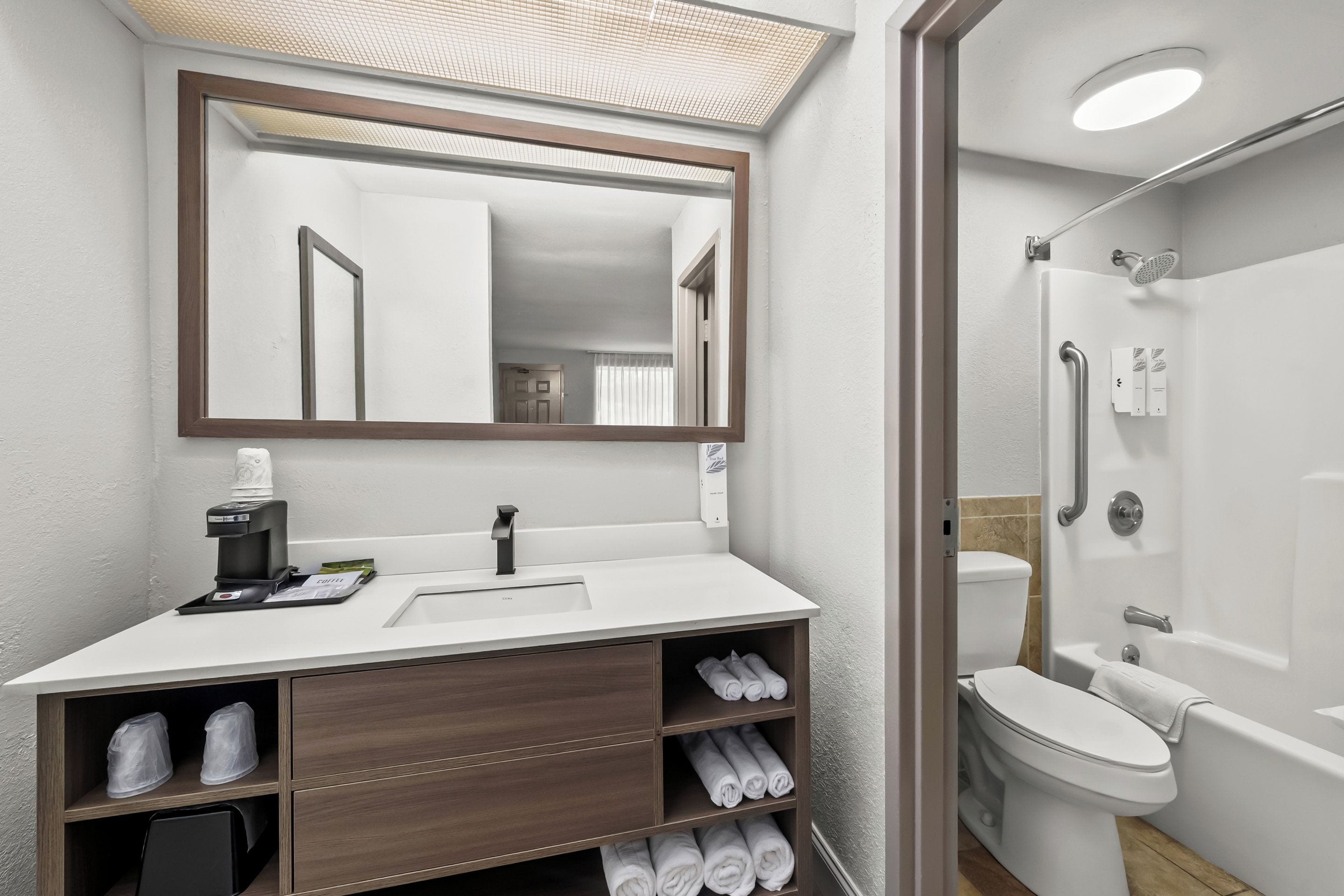 A modern bathroom with a white sink, mirror, and shower.