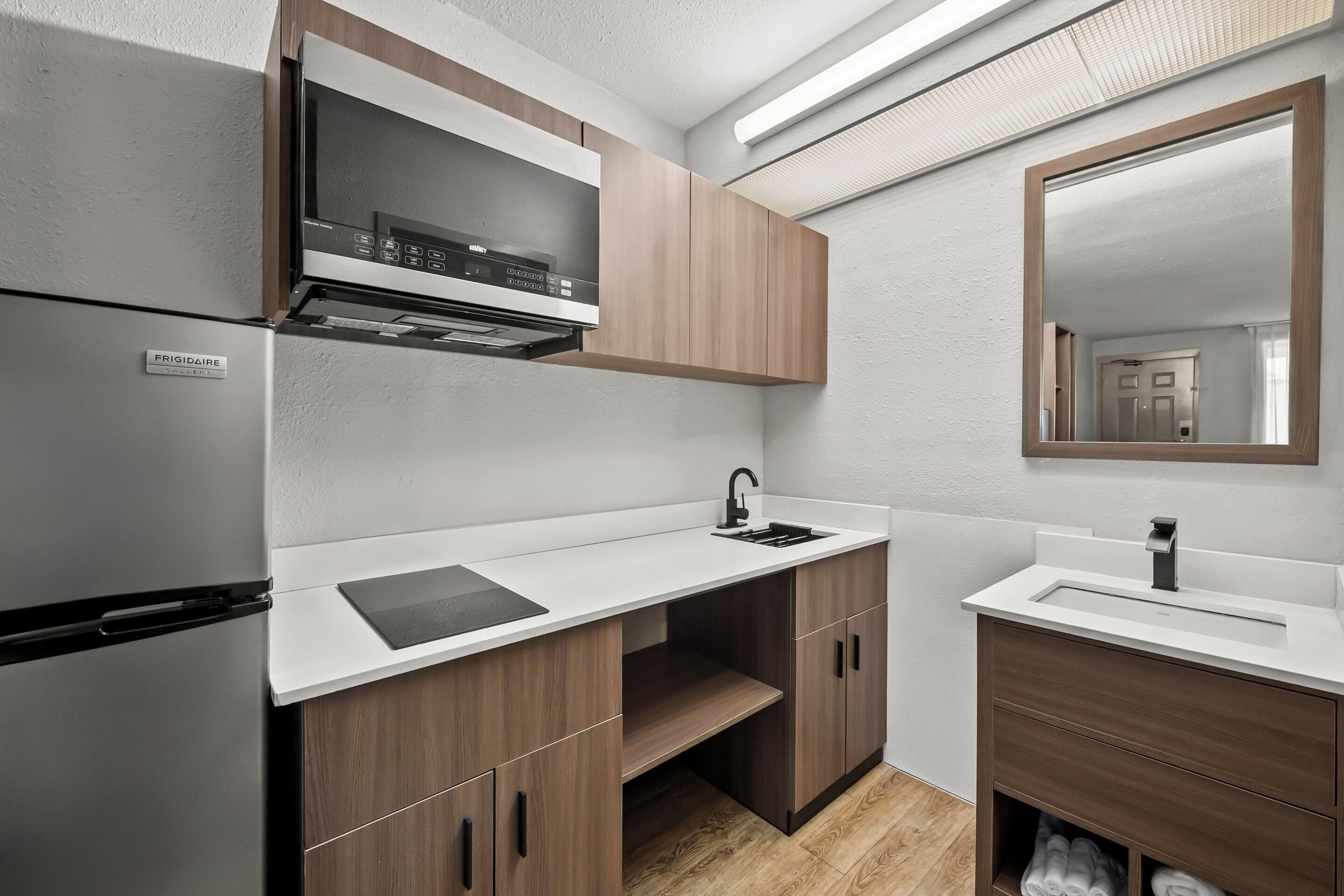 A compact kitchen with a built-in microwave, a sink, and wooden cabinets.
