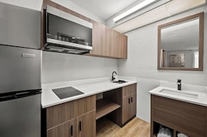Una cocina compacta con microondas integrado, un lavamanos y armarios de madera.