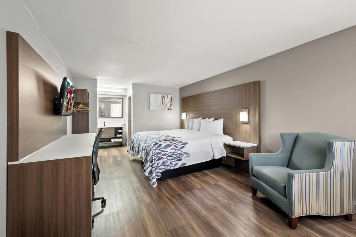 Een moderne hotelkamer met een groot bed, een bureau, een stoel en een aan de muur bevestigde televisie.