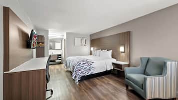 Une chambre d’hôtel moderne, dotée d’un grand lit, d’un bureau, d’une chaise et d’un téléviseur fixé au mur.