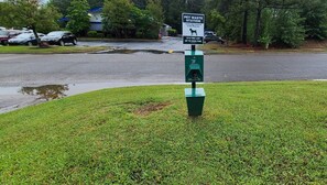 A pet waste station with a sign, a green trash bin, and a grassy area. - Red Roof Inn Sanford (Sanford)