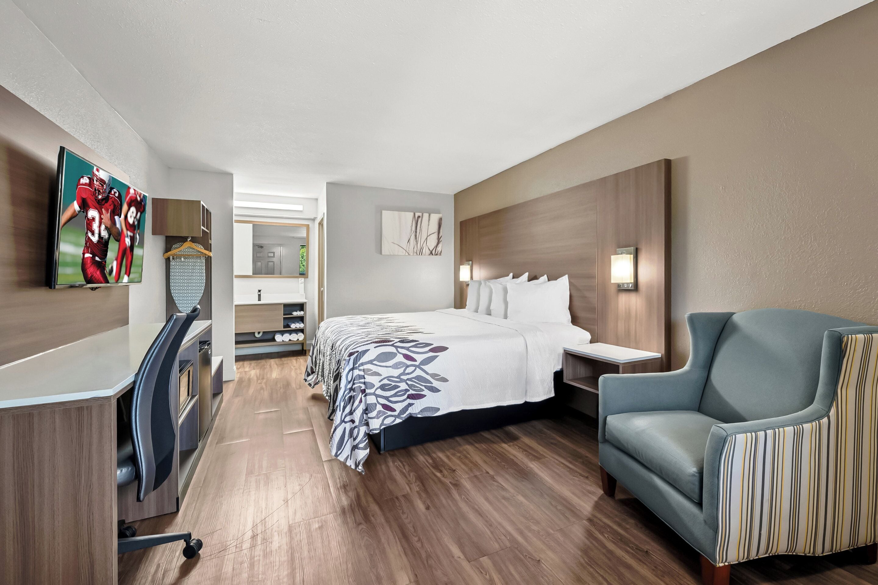 Una habitación de hotel moderna con cama, escritorio, silla y televisor.