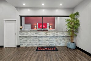 Een receptiegedeelte met een stenen muur, een Red Roof bord, een potplant en een deur.