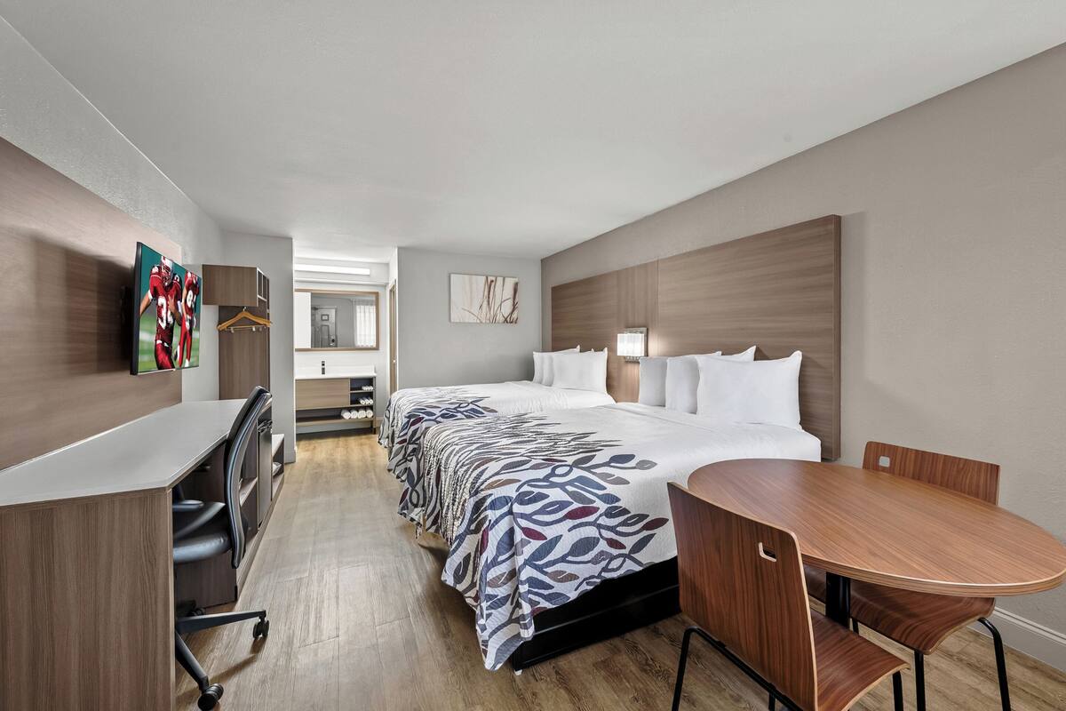 A hotel room with a large bed, a desk, and a dining table.