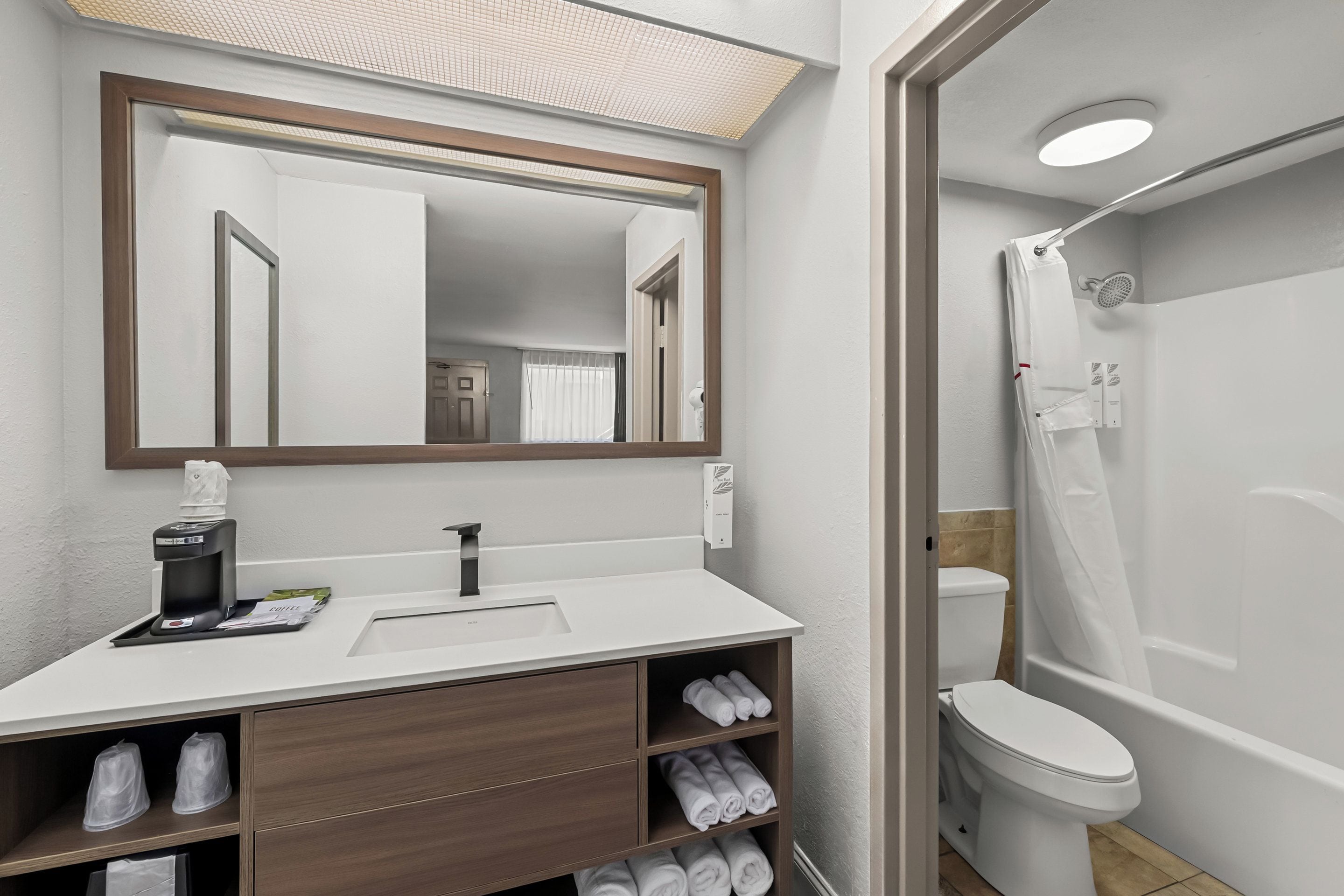 A modern bathroom with a white sink, a mirror, a toilet, and a shower.