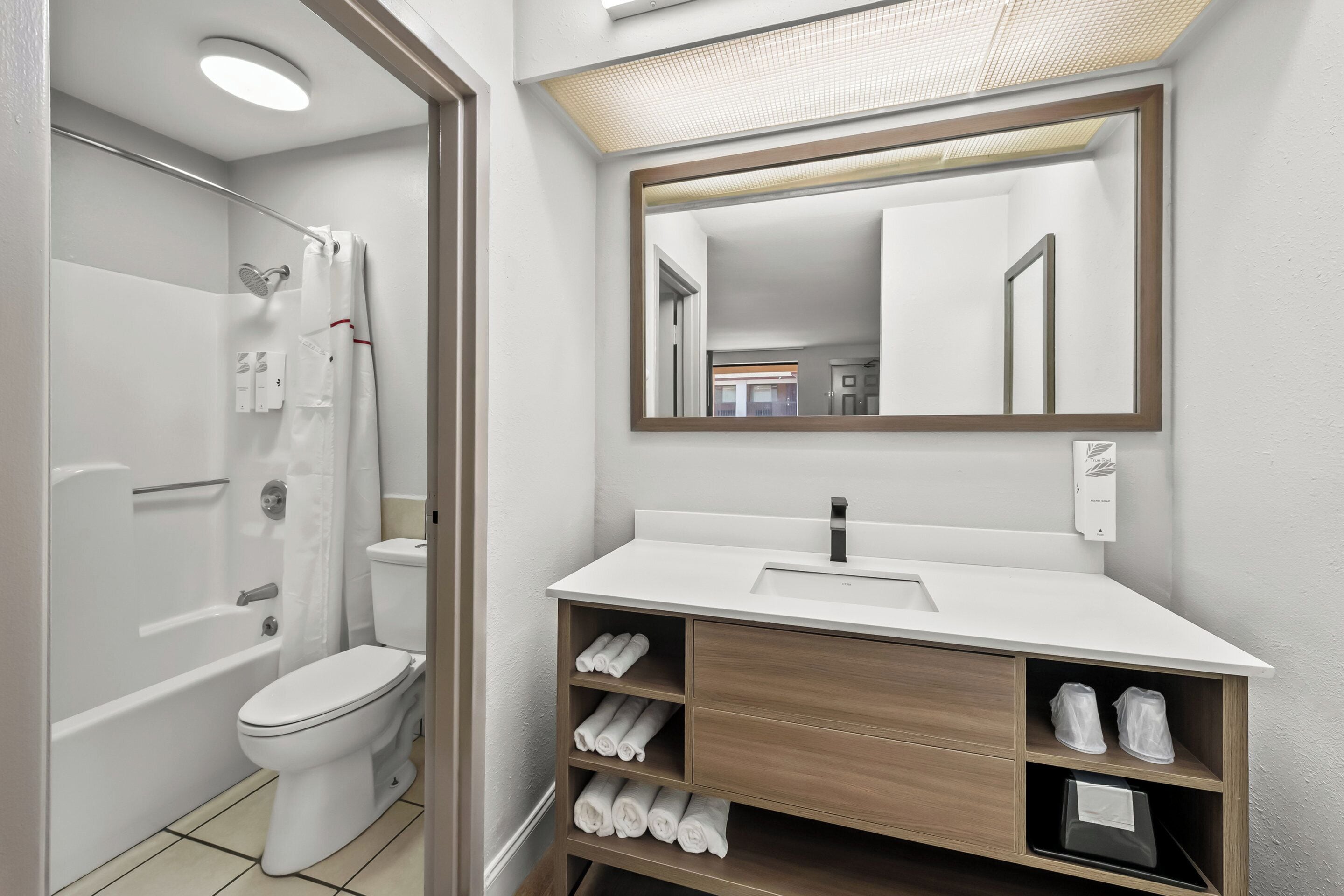 A modern bathroom with a bathtub, toilet, and vanity with a mirror.
