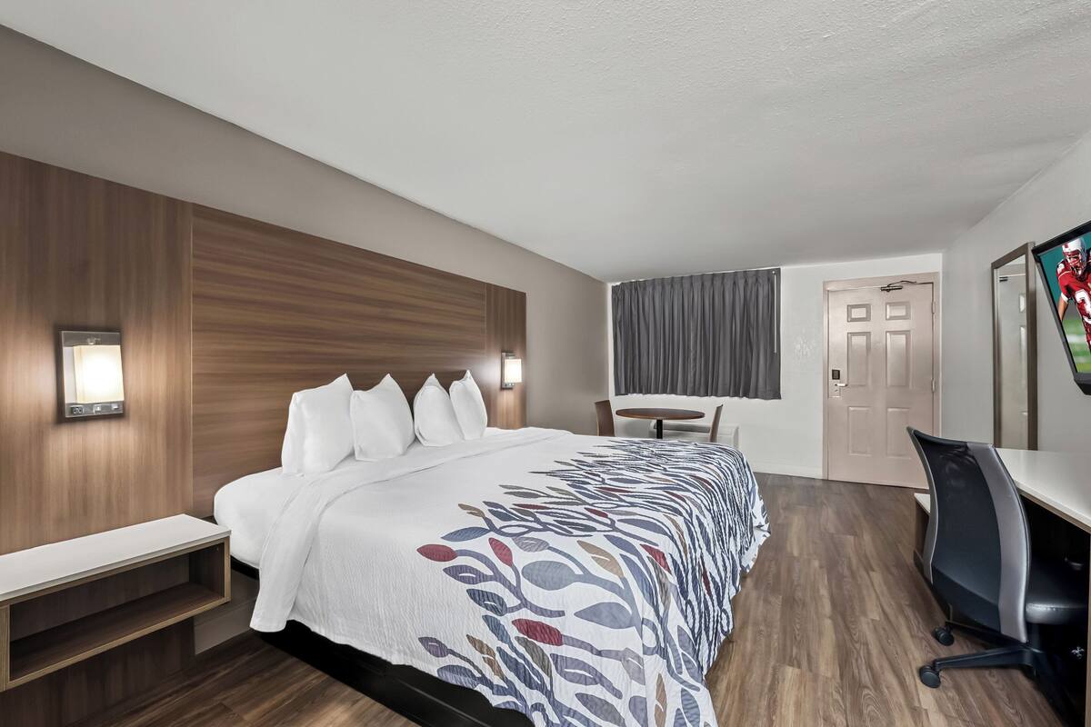 A modern hotel room with a large bed, a desk, and a chair.